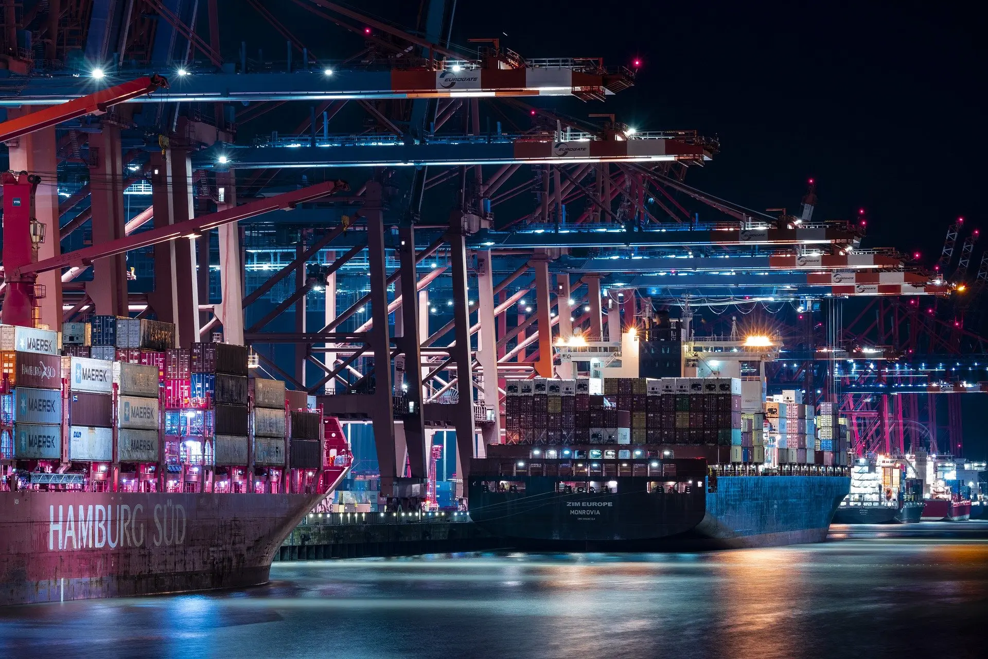 Containerhafen bei Nacht mit beleuchtetem Containerschiff